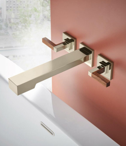 The Wall Mount Tub Filler from the Frank Lloyd Wright® Bath Collection by Brizo®, mounted on a red wall above a white tub.